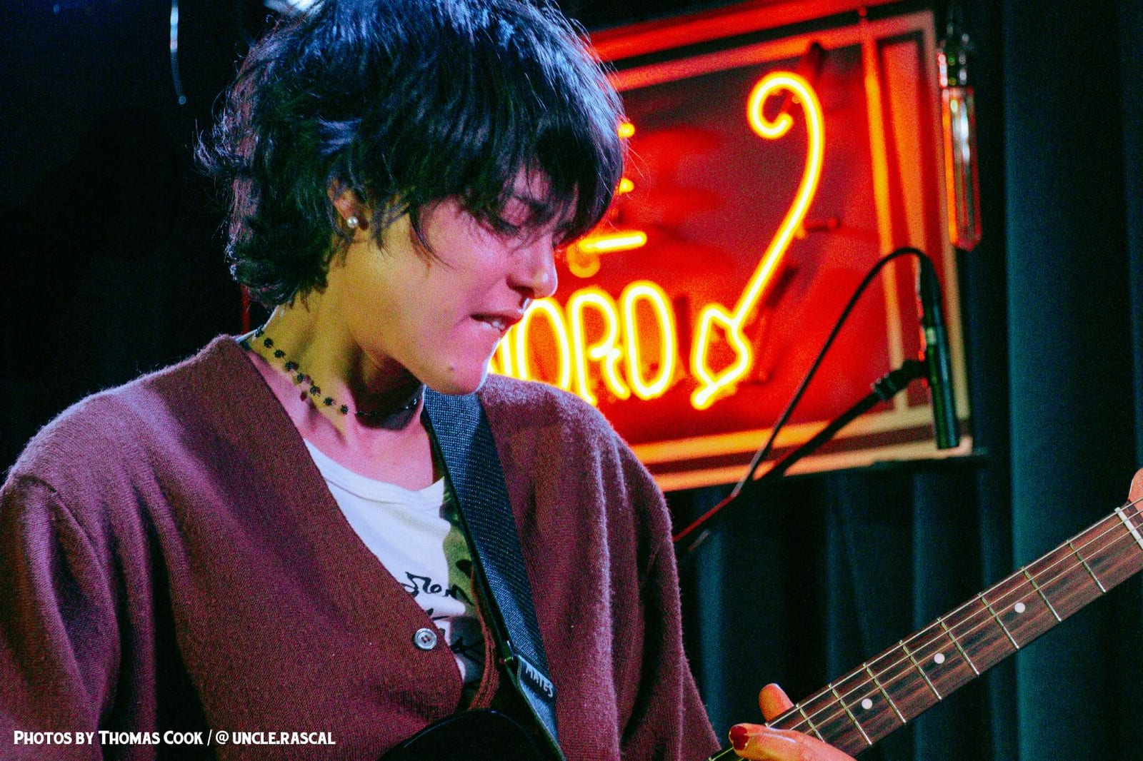 A guitarist close up, with the Du Nord neon behind